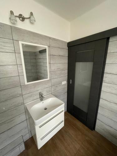 a bathroom with a white sink and a mirror at Apartmán SUŠICE 