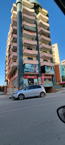 a silver car parked in front of a tall building at Charming Apartment Lushnje in Lushnjë