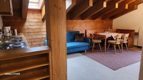 a living room with a blue couch and a table at Gasthof Starzelhaus in Mittelberg