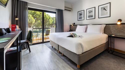 a hotel room with a large bed and a desk at The Magnolia Hotel in Quinta do Lago