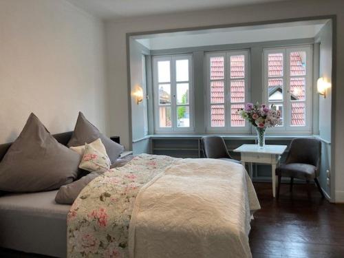 1 dormitorio con 1 cama, 1 mesa y 2 ventanas en Ferienwohnung Grete, en Münsingen
