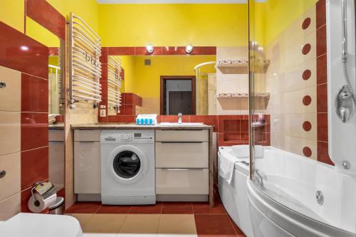 een badkamer met een wasmachine in een wastafel en een bad bij Malborska Metro Kondratowicza Apartment in Warschau