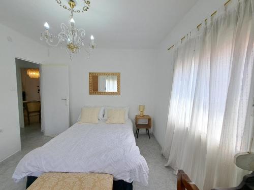 a white bedroom with a bed and a chandelier at Apartamento acogedor con wifi in Valencia