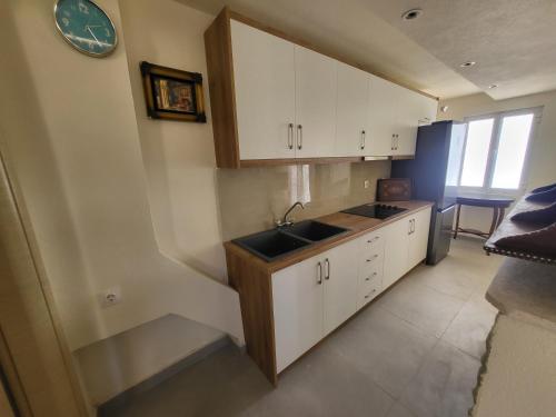 a kitchen with white cabinets and a sink and a clock at Villa Sotiri in Sarandë