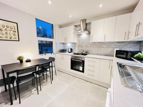 a kitchen with white cabinets and a black table and chairs at Battersea Studios by Sleepy in London