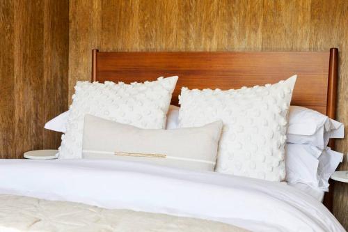 a bed with white pillows and a wooden headboard at Wonder Wagon at Trelan Farm in Mold