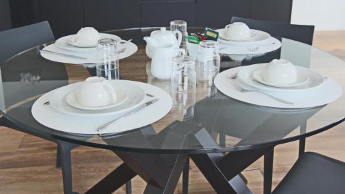 a glass dining room table with white plates and silverware at Hotel Corte Santa Libera in San Fedele Intelvi
