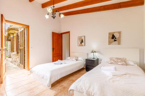 2 bedden in een kamer met witte muren en houten plafonds bij Navarro in Pollença