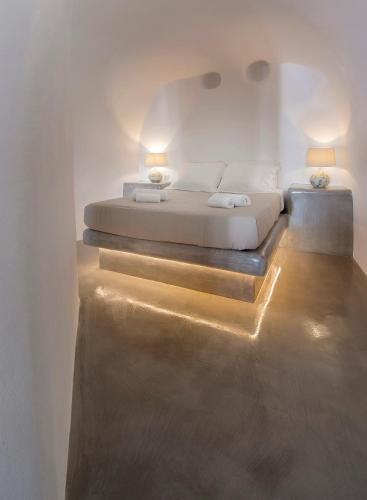 a bedroom with a bed with lights on the floor at AQUA SERENITY LUXURY SUITES SANTORINI in Foinikiá
