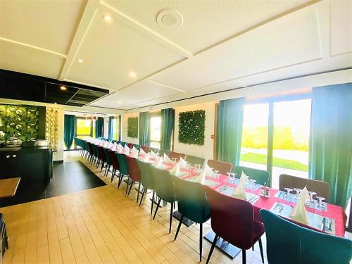 un restaurant avec une longue rangée de tables et de chaises dans l'établissement Hôtel Restaurant Kyriad de Péronne, à Péronne