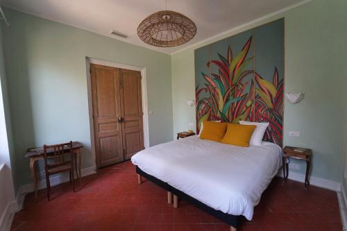 a bedroom with a bed with a painting on the wall at Domaine de Lanis - Maison d'hôtes avec parc et piscine in Castelnaudary