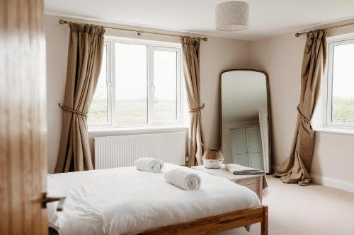 a bedroom with two beds and a mirror at Rodham House, Fenland Retreats at Willow Grange Farm in Cambridge