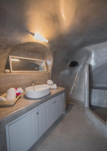 a bathroom with a white sink in a cave at AQUA SERENITY LUXURY SUITES SANTORINI in Foinikiá