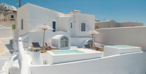 a balcony with chairs and a swimming pool on a house at AQUA SERENITY LUXURY SUITES SANTORINI in Foinikiá
