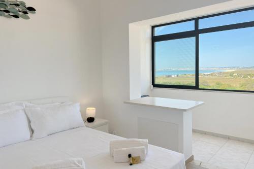 ein weißes Schlafzimmer mit einem weißen Bett und einem großen Fenster in der Unterkunft Studio on Alvor's Beach by amcf in Alvor