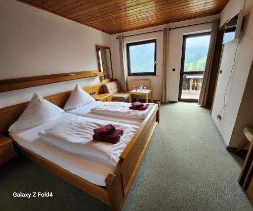 una camera da letto con lenzuola bianche e asciugamani viola di Gasthof Starzelhaus a Mittelberg