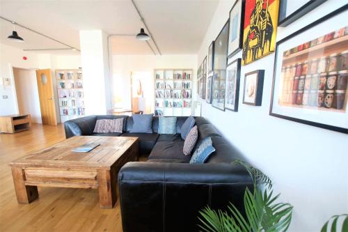 a living room with a black couch and a wooden table at Funky urban two bed flat in the heart of Bristol in Bristol