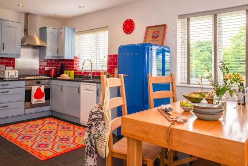cocina con mesa y nevera azul en Bosinver Farm Cottages Buddleia en St Austell