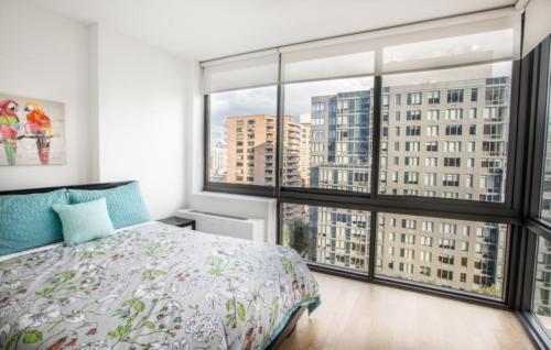 een slaapkamer met een bed en grote ramen bij Modern 2 BR with Rooftop Lounge in New York
