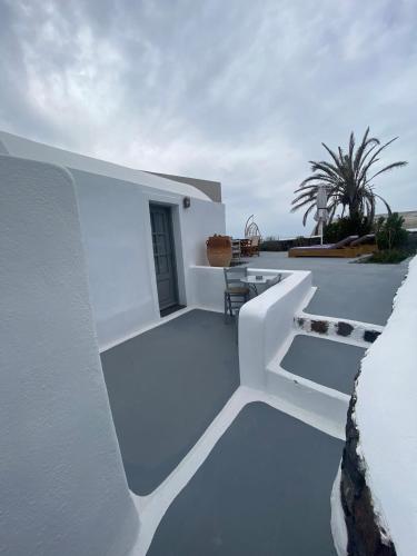 a white house with a balcony with a table at AQUA SERENITY LUXURY SUITES SANTORINI in Foinikiá