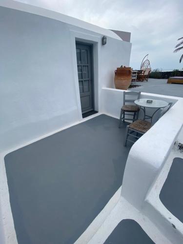 a white house with a balcony with a table and chairs at AQUA SERENITY LUXURY SUITES SANTORINI in Foinikiá