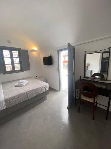 a bedroom with a bed and a desk and a mirror at AQUA SERENITY LUXURY SUITES SANTORINI in Foinikiá
