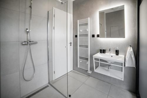 a bathroom with a shower and a sink and a mirror at Piano apartments - LICITY in Žilina