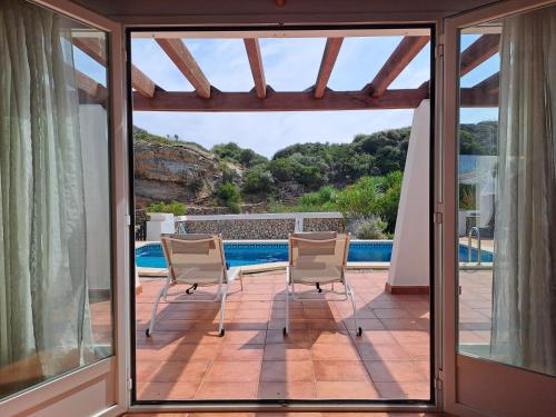 a patio with two chairs and a swimming pool at Villa Xalina - Piscina / bbq / jardín in Fornells