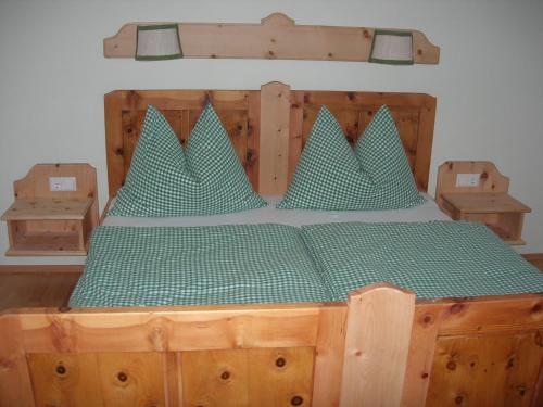 una cama de madera con almohadas verdes encima. en Polzhof, en Sankt Andrä im Lungau