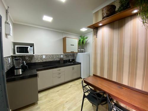 a kitchen with a refrigerator and a table in it at Hotel APART Zuccolotto 2 in Aracruz