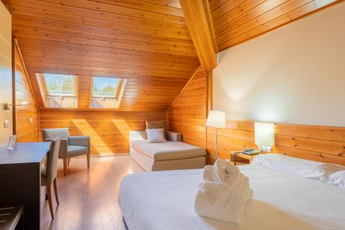 Pokój z 2 łóżkami, krzesłem i kanapą w obiekcie IBERIK Augas Santas Balneario & Golf w mieście Pantón