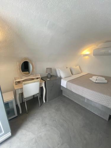 a bedroom with a bed and a desk with a desk at AQUA SERENITY LUXURY SUITES SANTORINI in Foinikiá