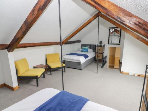 a bedroom with two beds and two chairs in a attic at Little Rosemount in Tenby