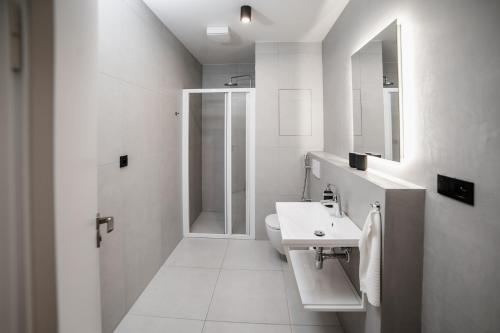 a white bathroom with a sink and a shower at Piano apartments - LICITY in Žilina
