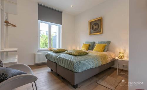斯帕的住宿－LeValenVille，一间卧室配有一张带黄色枕头的床和一扇窗户