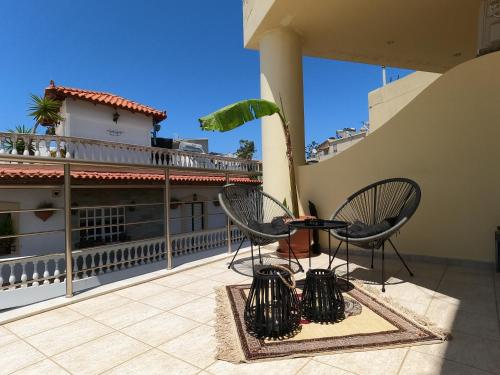 a patio with two chairs and a plant on a balcony at KND Living Concept - Apartment in Heraklio