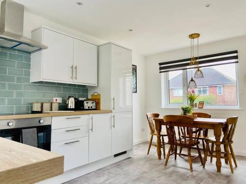 a kitchen with white cabinets and a table with chairs at uSnooz - New for 2023! Cosy house, 2 bed in Hipperholme