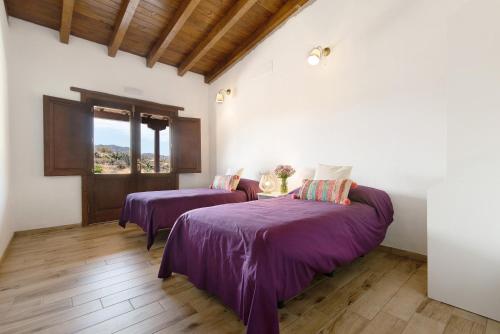 a bedroom with two beds with purple sheets and a window at El Algarrobero in Santa Lucía