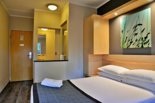 a bedroom with a large white bed and a mirror at Road Lodge Rivonia in Johannesburg