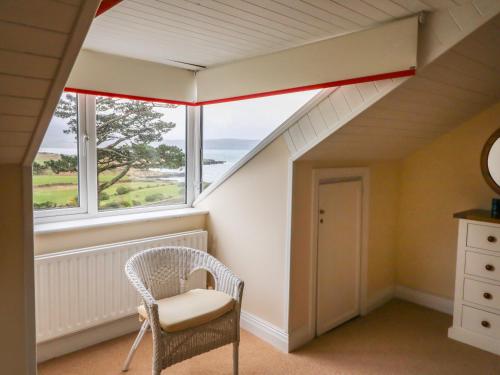 an attic room with a chair and a window at Whispering Pines in Bantry