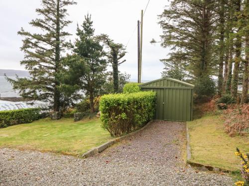 a green shed on the side of a gravel driveway at Whispering Pines in Bantry