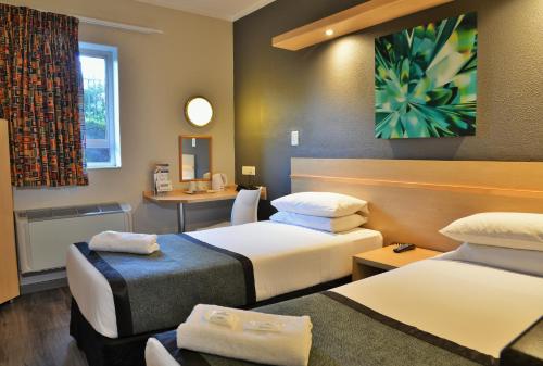 a hotel room with two beds and a table at Road Lodge Rivonia in Johannesburg