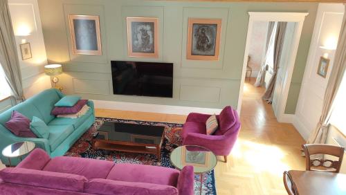 ein Wohnzimmer mit lilafarbenen Möbeln und einem Flachbild-TV in der Unterkunft Royal Jono st. Apartment in Klaipėda