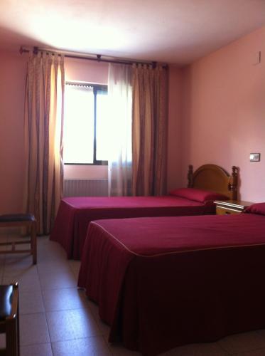 a hotel room with two beds and a window at Hostal Tio Pepe I in Bembibre