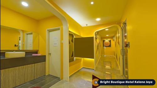 a yellow bathroom with a shower and a sink at Bright Boutique Hotel Kelana Jaya in Petaling Jaya