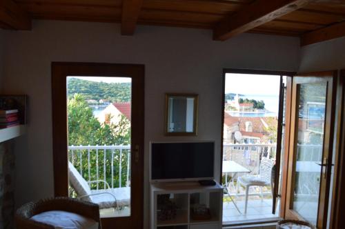 a living room with a tv and a balcony at Studio apartman Tomi - seaview in Vis