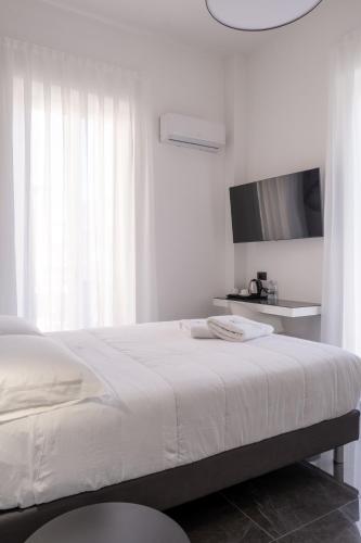 a white bedroom with a bed and a tv at Domea Superior Rooms Bed and Breakfast in Reggio Calabria