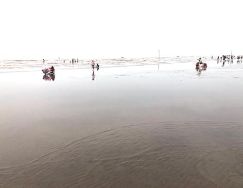 a group of people walking on the beach at HaiAu Hotel in Quất Lâm