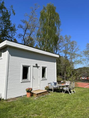 un pequeño cobertizo blanco con una mesa de picnic y un banco en Lilla huset med tennisbana, 