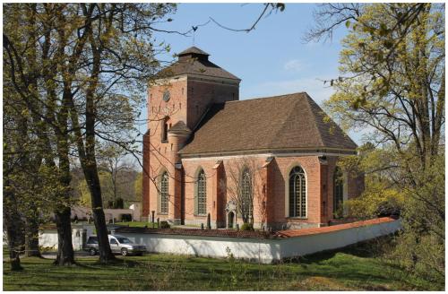 una gran iglesia de ladrillo rojo con una torre de reloj en Lilla huset med tennisbana, 